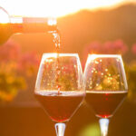 Red wine being poured into glasses at sunset